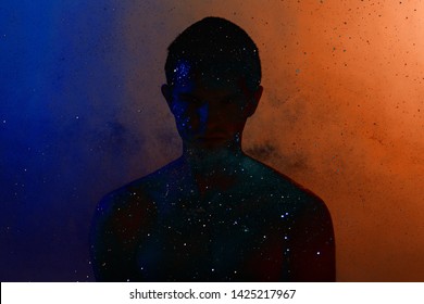 High Fashion Model Man In Colorful Bright Sparkles And Neon Lights Posing In Studio, Portrait Man, Trendy Glowing Make-up. Art Design Colorful Make Up. Glitter Vivid Neon Makeup