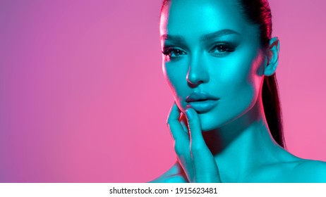 High fashion model metal silver lips and face woman in colorful bright neon UV blue and purple lights, posing in studio, beautiful girl, glowing makeup, colorful makeup. Glitter Bright Neon Makeup - Shutterstock ID 1915623481