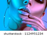 High Fashion model metallic silver lips woman in colorful bright neon blue and purple lights posing in studio, beautiful girl, trendy glowing make-up, colorful metal make up. Glitter Vivid neon makeup