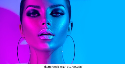 High Fashion model metallic silver lips and face woman in colorful bright neon uv blue and purple lights, posing in studio, beautiful girl, glowing make-up, colorful make up. Glitter Vivid neon makeup - Shutterstock ID 1197309358