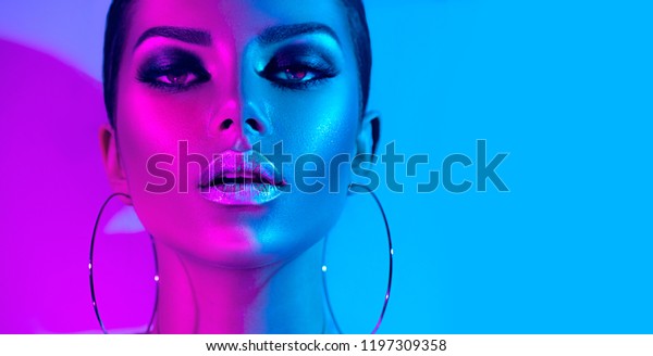 High Fashion model metallic silver lips and face\
woman in colorful bright neon uv blue and purple lights, posing in\
studio, beautiful girl, glowing make-up, colorful make up. Glitter\
Vivid neon makeup