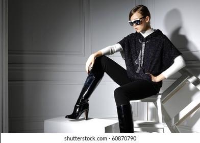 High Fashion Model In Modern Dress Sitting In The Studio