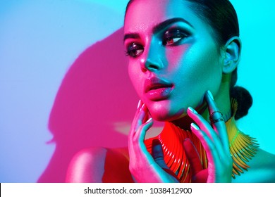 High Fashion model woman in colorful bright lights posing in studio, portrait of beautiful sexy girl with trendy make-up and manicure. Art design, colorful make up. Over colourful vivid background.