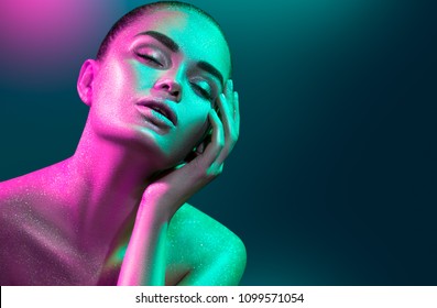 High Fashion model woman in colorful bright sparkles and neon lights posing in studio, portrait of beautiful sexy girl, trendy glowing make-up. Art design colorful make up. Glitter Vivid neon makeup