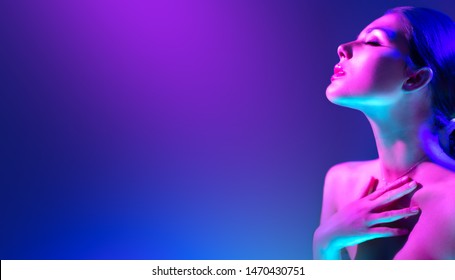 High Fashion model woman in colorful bright neon lights posing in studio, night club. Portrait of beautiful girl in UV. Art design colorful make up. On colourful vivid background