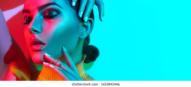 High Fashion model woman in colorful bright lights posing, portrait of beautiful sexy girl with trendy make-up and manicure, glowing skin. Art design, colorful make up. Over multicolor background