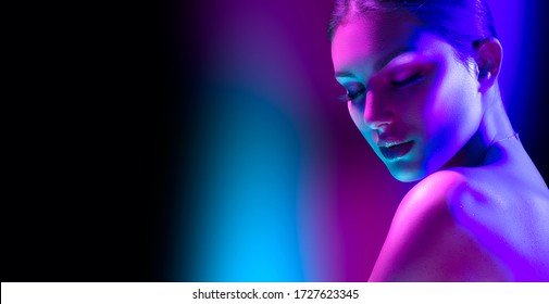 高级时装模特女人穿着五颜六色的明亮霓虹灯摆在工作室，夜总会。紫外线漂亮女孩的肖像。艺术设计丰富多彩的化妆。在色彩鲜艳的生动背景上，艺术设计。