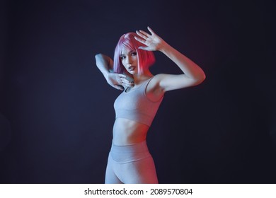 High Fashion Model Woman In Colorful Bright Neon Lights Posing And Looking At Camera Isolated On Party Dark Studio Background. Portrait Of Beautiful Girl In UV. Female In Glasses Of Virtual Reality.