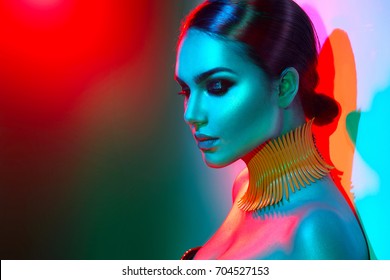 High Fashion model woman in colorful bright lights posing, portrait of beautiful sexy girl with trendy make-up. Art design, colorful make up. Over colourful vivid background. Night club dancer