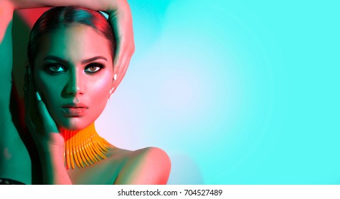 High Fashion model woman in colorful bright lights posing in studio, portrait of beautiful sexy girl with trendy make-up and manicure. Art design, colorful make up. Over colourful vivid background