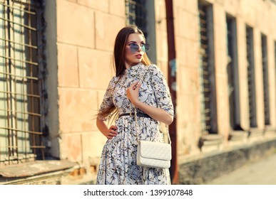 high fashion outdoor portrait of young woman. Light dress, belt, long hair, sunglasses