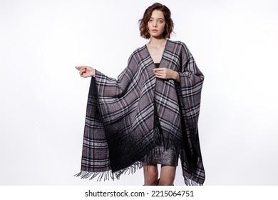 High Fashion Photo Of A Beautiful Elegant Young Woman In A Pretty Gray Poncho, Metallic Silver Skirt, Suede Boots Posing Over White Background. Make Up, Hairstyle. Slim Figure.