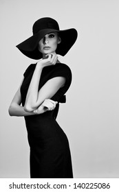 High Fashion Portrait Of Elegant Woman In Black And White Hat And Dress. Studio Shot