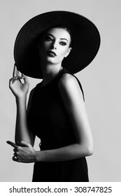 High Fashion Portrait Of Elegant Woman In Black And White Hat And Dress. Studio Shot