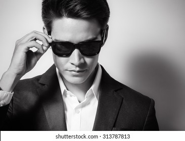 High fashion portrait of male model wearing sunglasses and a suit. 