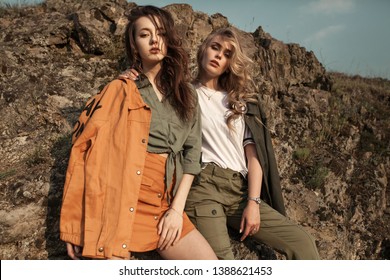 High fashion portrait of two stylish beautiful woman in trendy jackets and jeans posing outdoor.  
