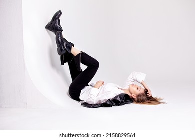 High fashion portrait of young elegant woman in a black leather jacket, trousers and white shirt. Studio shot.