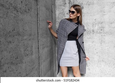 High Fashion Portrait Of Young Elegant Woman Outdoor. Grey Coat, Cat Eye Sunglasses, Grey Wall Background