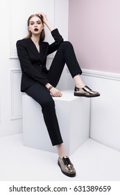 High Fashion Portrait Of Young Elegant Woman In Black Suit And Loafers. Studio Shot.