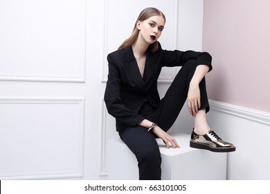 High Fashion Portrait Of Young Elegant Woman In Black Suit And Loafers. Studio Shot.