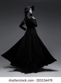 High Fashion Shot Of Elegant Woman In A Hat And Long Fluttering Dress. Black And White Image