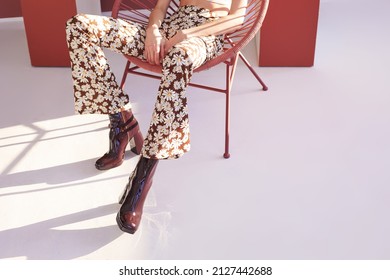 High Fashion Spring Portrait Of Young Elegant Woman In Retro Outfit. Retro Pants, Panama Hat, Leather Boots, Flowers. 60s, 70s Style Fashion Look