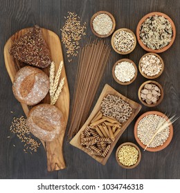 High Fiber Health Food With Whole Grain Bread, Pasta, Cereals And Grains On An Olive Wood Board And In Wooden And Terracotta Bowls. Rustic Background On Oak, Top View.