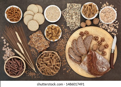 High fibre health food with whole wheat walnut and rye bread, whole grain pasta, oatmeal and seeded crackers, barley oats, bran flakes and wheat sheath on lokta paper background. - Powered by Shutterstock