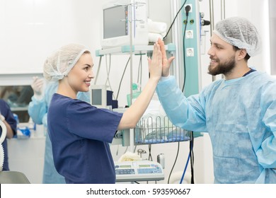 High Five! Attractive Happy Female Nurse Smiling High Fiving With A Male Surgeon After Operating Their Patient Successfully Hospital Clinic Teamwork Medicine Profession Scrubs Team Career Healthcare 