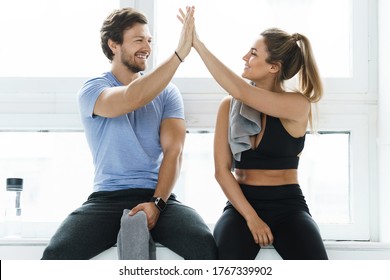 High Five Between Man And Woman In The Gym After Fitness Workout. Personal Trainer And His Client Achieving Results During A Training.