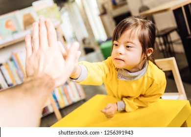 High Five. Dark-eyed Sunny Child Giving High Five To Her Teacher In The Inclusive Kindergarten