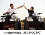 High five gesture. Father and daughter are with ATV outdoors.