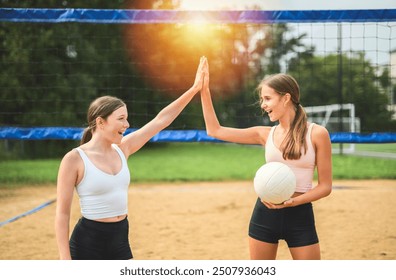 A High five, two women play beach volleyball in summer - Powered by Shutterstock