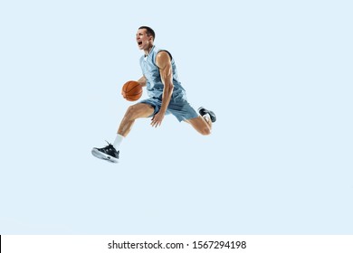 High flight. Young caucasian basketball player of team in action, motion in jump isolated on blue background. Concept of sport, movement, energy and dynamic, healthy lifestyle. Training, practicing. - Powered by Shutterstock