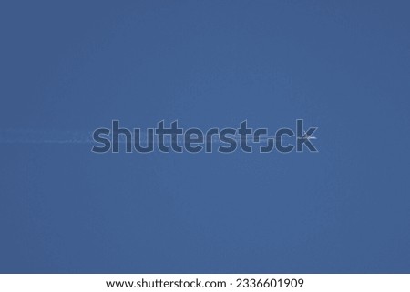 high flying passenger plane with condensation trails, blue sky background