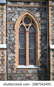 A High Gothic Pointed Window On The Wall Of The Outdoor Stone Wall