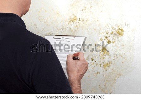 High humidity damage concept: man with an inspection checklist in front of a white wall overgrown with mold, mildew or fungus.