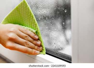 high humidity in the house. hand wipes off water condensation from plastic window glass in the room - Powered by Shutterstock