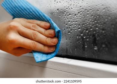 high humidity in the house. hand wipes off water condensation from plastic window glass in the room - Powered by Shutterstock