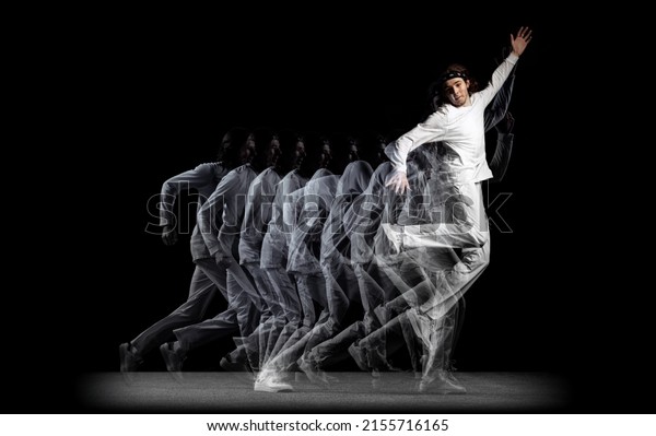 High jumps. Young man, hip-hop dancer in action,\
motion isolated on dark background with sroboscope effect. Youth\
culture, hip-hop, movement, style and fashion. Modern street\
dancing style