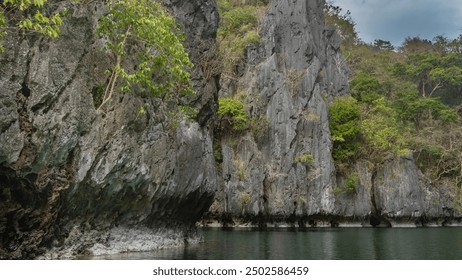 High karst rocks surround the emerald lagoon. Green tropical vegetation on steep gray furrowed slopes. The blue sky. Philippines. Palawan. Small lagoon. Bacuit Bay. El Nido. - Powered by Shutterstock