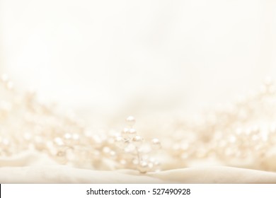 High key image of pearl covered branches on light fabric with shallow depth of field.

