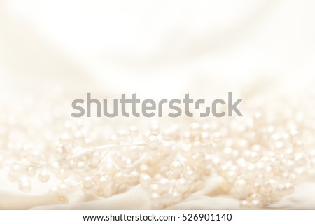 High key image of pearl covered branches on light fabric with shallow depth of field.