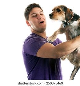 High Key Portrait Of A Young Man Holding A Cute Mixed Breed Dog Isolated Over White. 