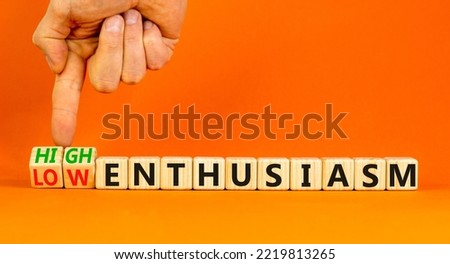 High or low enthusiasm symbol. Concept words High enthusiasm and Low enthusiasm on wooden cubes. Businessman hand. Beautiful orange background. Business high or low enthusiasm concept. Copy space.