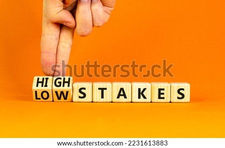High or low stakes symbol. Concept words High stakes and Low stakes on wooden cubes. Businessman hand. Beautiful orange table orange background. Business high or low stakes concept. Copy space.