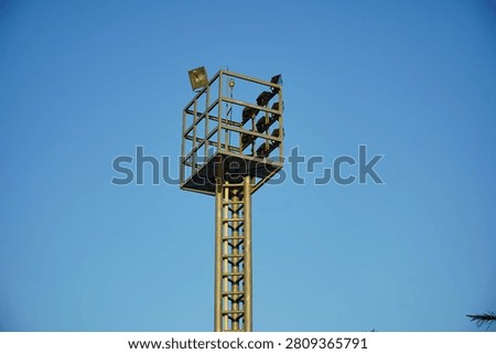 High mast floodlight tower with multiple LED floodlights against a clear blue sky