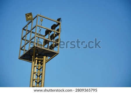 High mast floodlight tower with multiple LED floodlights against a clear blue sky