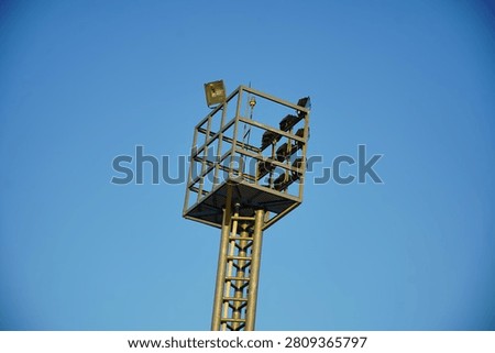High mast floodlight tower with multiple LED floodlights against a clear blue sky