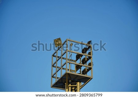 High mast floodlight tower with multiple LED floodlights against a clear blue sky